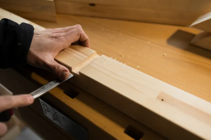 Detailansicht: Holzbalken wird mit Meißel bearbeitet