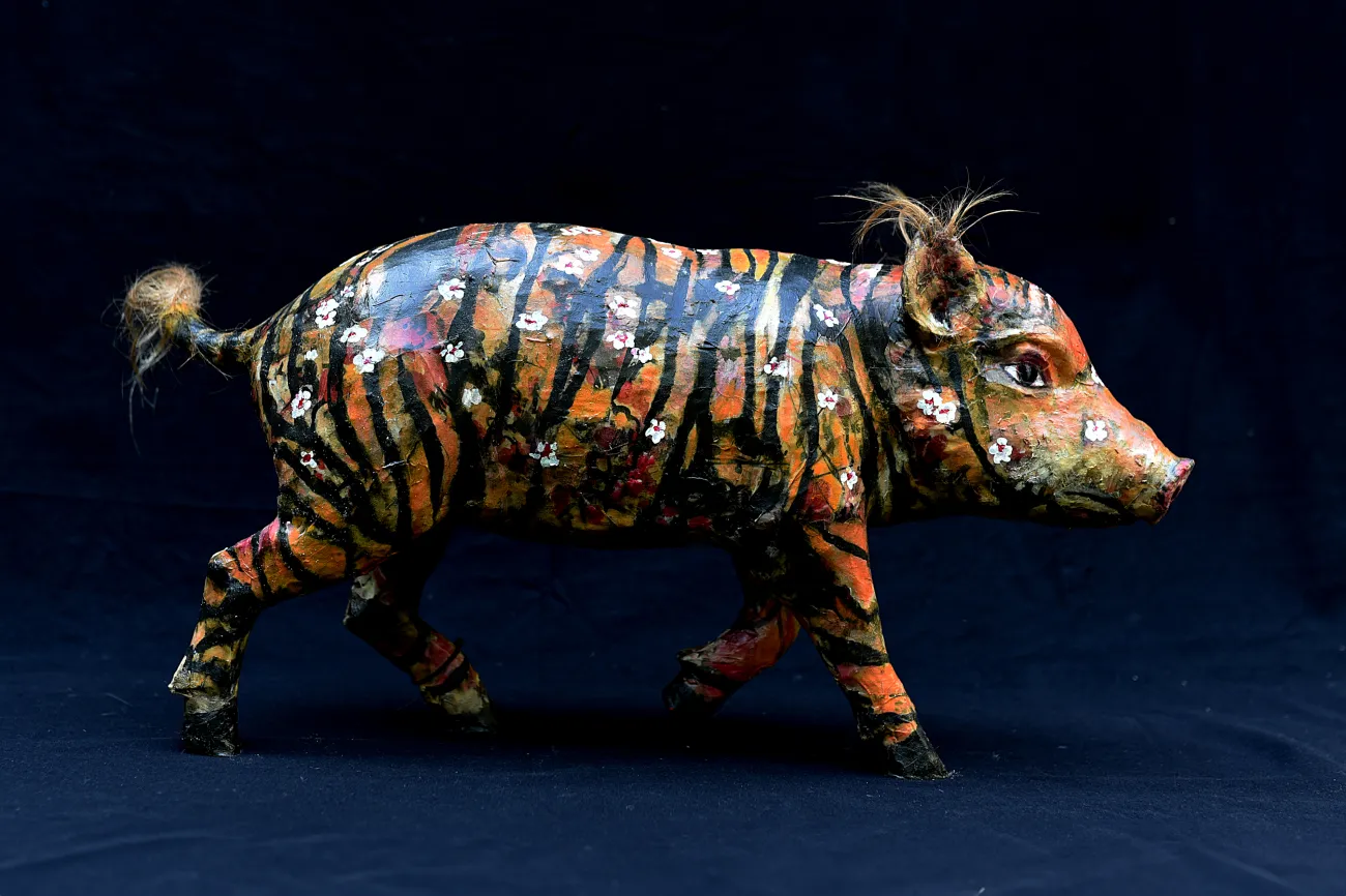 Schwein mit tigerartigem Muster in Orange, Schwarz und Weiß, verziert mit weißen Blumen