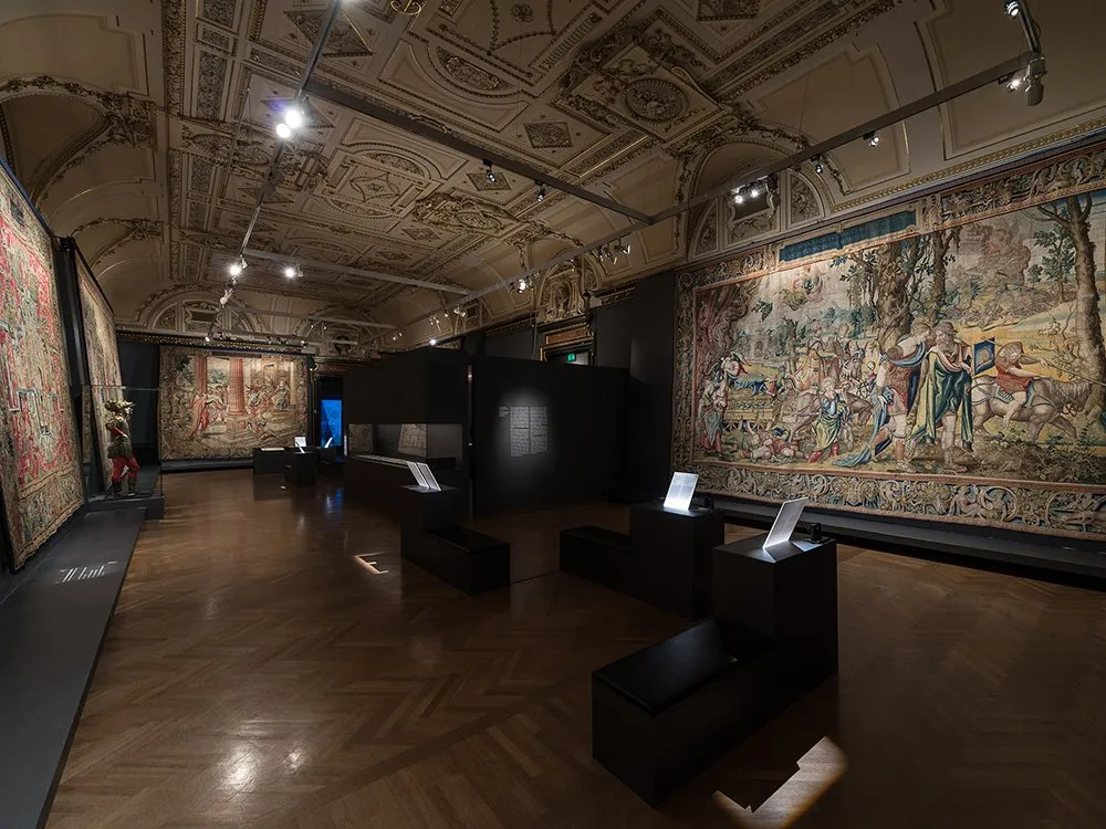 Ausstellungsraum: riesige Gemälde an Wänden, schwarze Podeste in Mitte